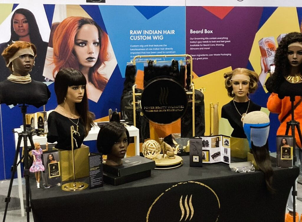 A display of mannequins and wigs at a trade show.